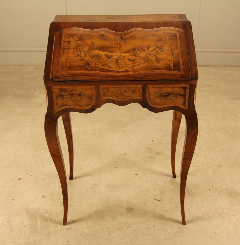 A 19th-century Italian walnut writing bureau featuring floral marquetry inlay, a slanted fall front, and slender cabriole legs. View V