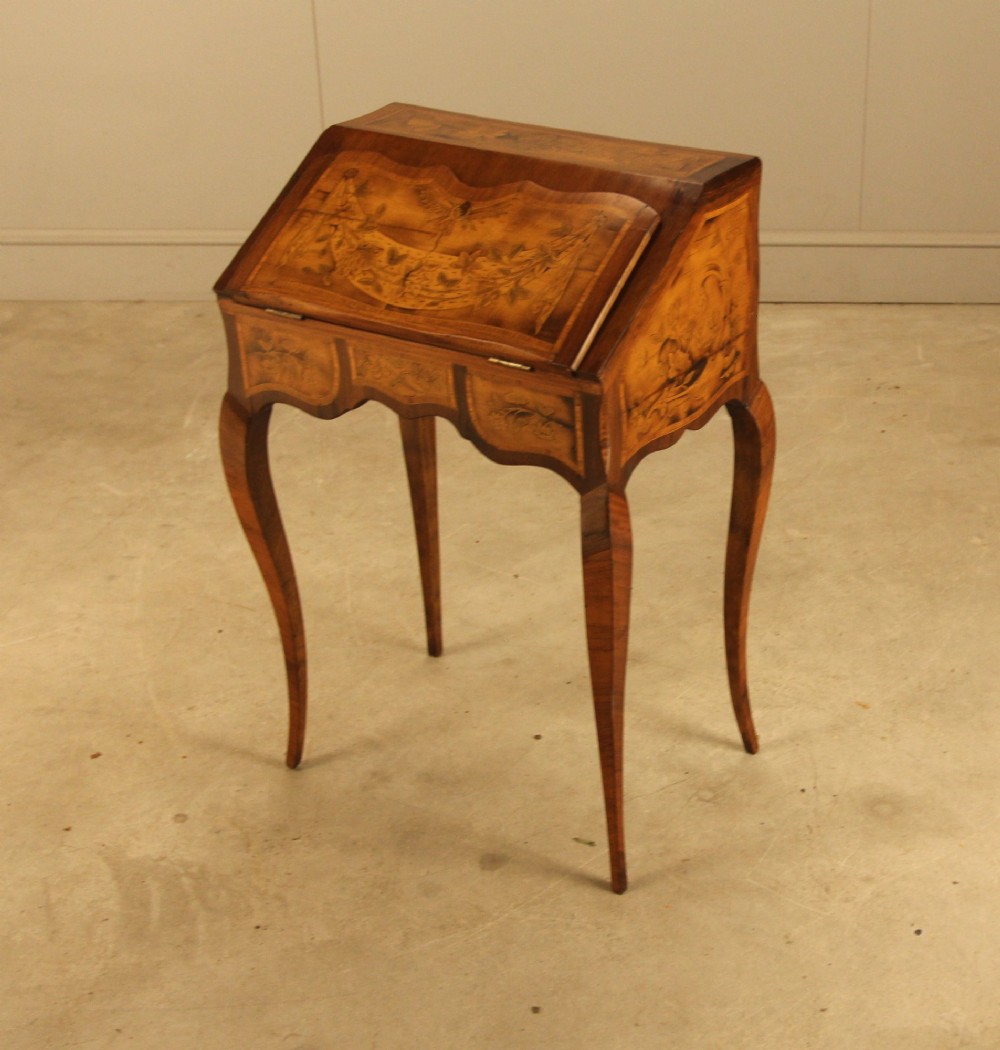 A 19th-century Italian walnut writing bureau featuring floral marquetry inlay, a slanted fall front, and slender cabriole legs. View VI