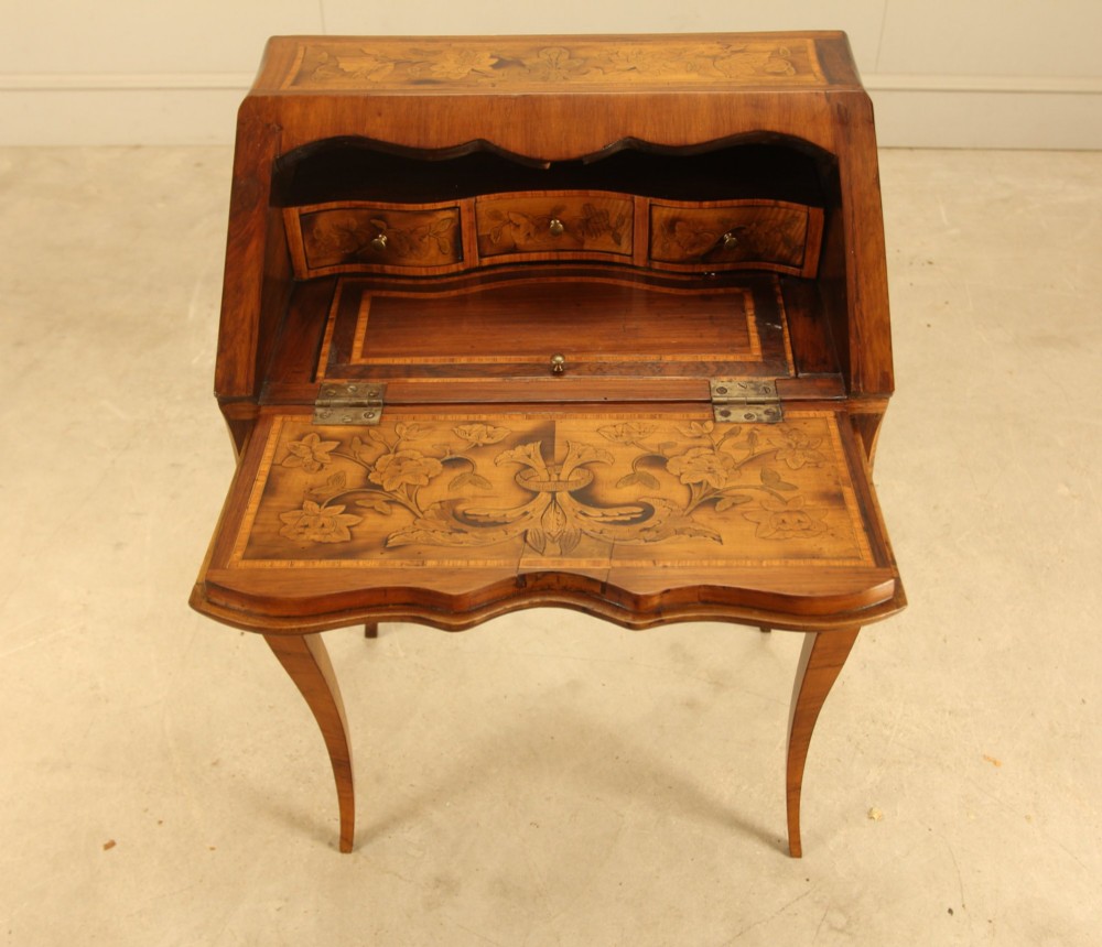 A 19th-century Italian walnut writing bureau featuring floral marquetry inlay, a slanted fall front, and slender cabriole legs. View VII