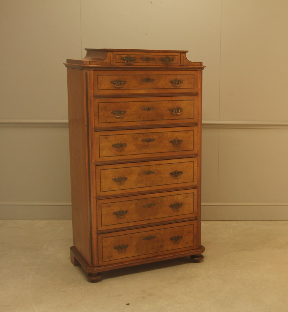 A tall 19th-century Swedish burr walnut chest of drawers featuring seven drawers, crossbanded inlay, ornate brass handles, and a stepped top section. View II