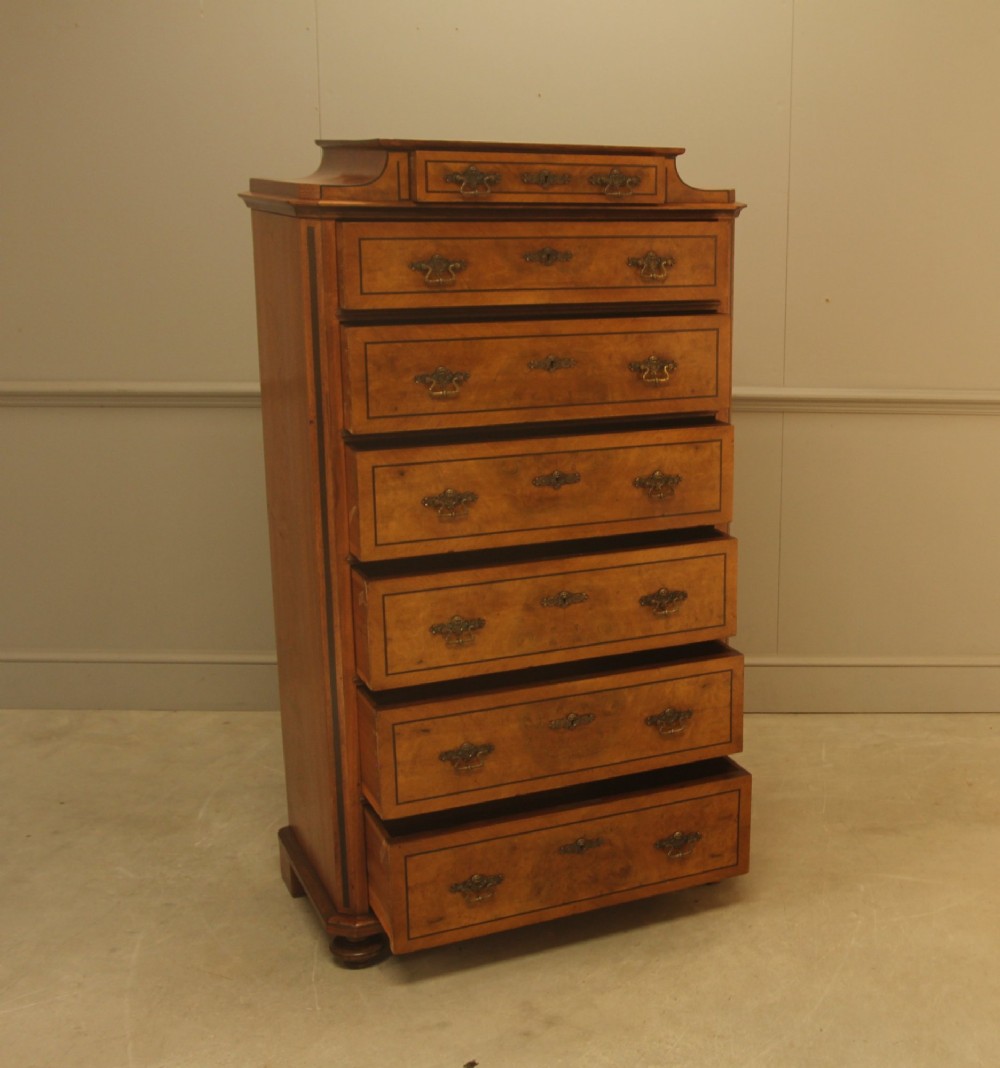 A tall 19th-century Swedish burr walnut chest of drawers featuring seven drawers, crossbanded inlay, ornate brass handles, and a stepped top section. View III