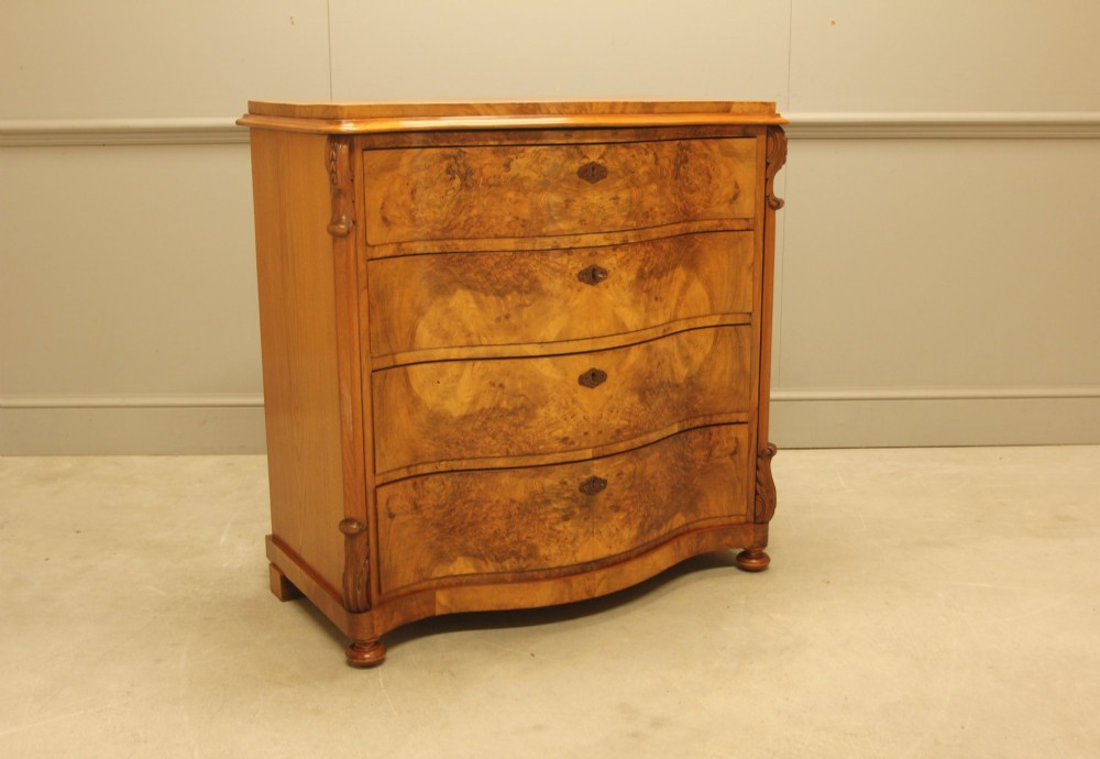 A 19th-century Swedish burr walnut chest of drawers featuring a serpentine front, four graduated drawers, brass escutcheons, and carved side pilasters. View II