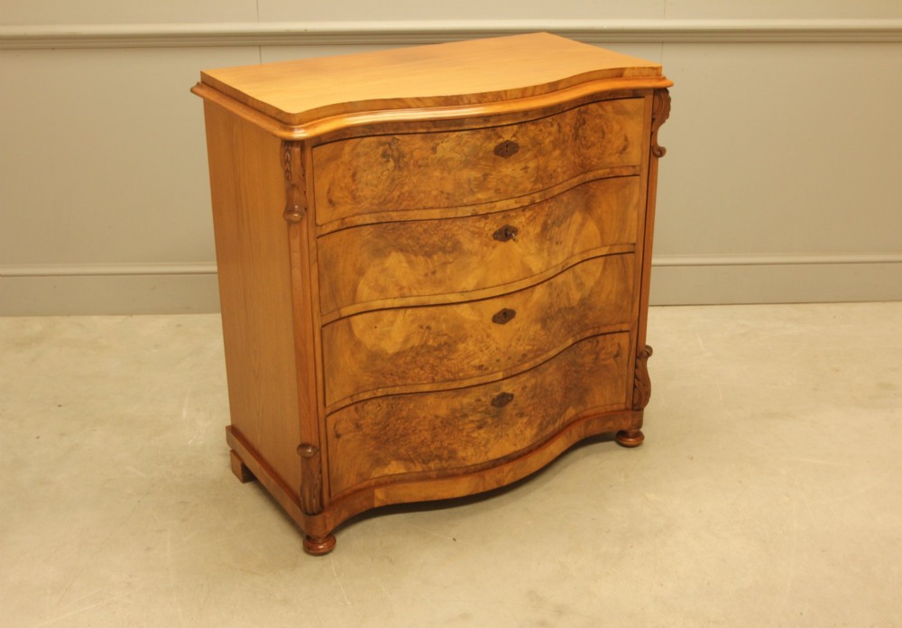 A 19th-century Swedish burr walnut chest of drawers featuring a serpentine front, four graduated drawers, brass escutcheons, and carved side pilasters. View III
