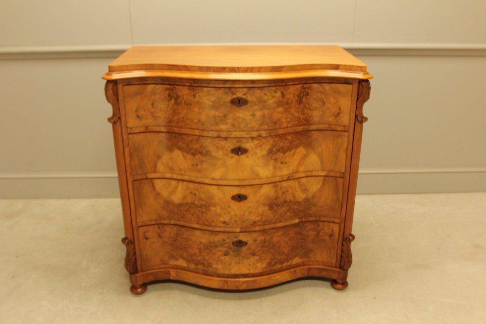 A 19th-century Swedish burr walnut chest of drawers featuring a serpentine front, four graduated drawers, brass escutcheons, and carved side pilasters. View VI