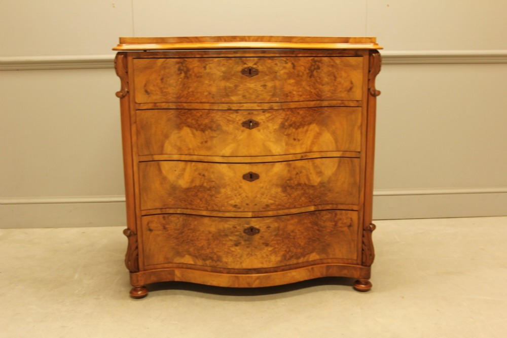A 19th-century Swedish burr walnut chest of drawers featuring a serpentine front, four graduated drawers, brass escutcheons, and carved side pilasters. View VII