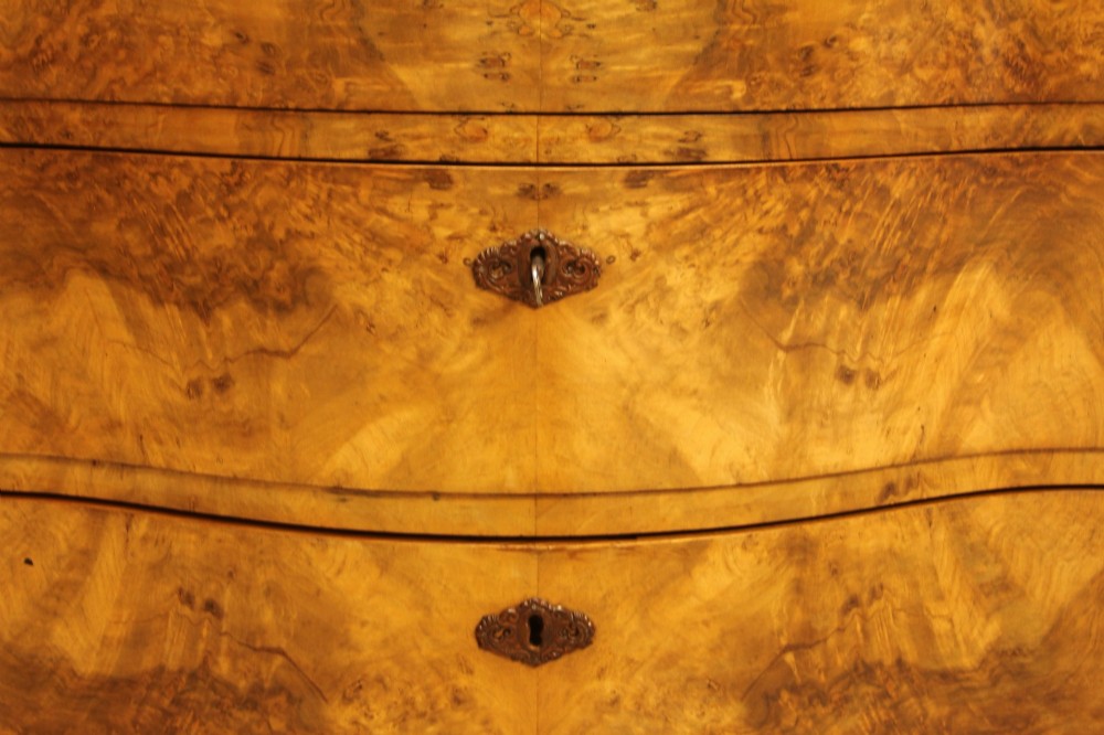 A 19th-century Swedish burr walnut chest of drawers featuring a serpentine front, four graduated drawers, brass escutcheons, and carved side pilasters. View IX