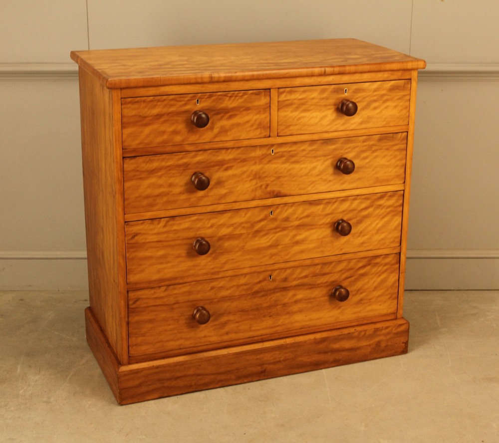 A Victorian stained birch chest of drawers featuring a two short over three long drawer configuration with turned wooden knobs and a solid plinth base. View V