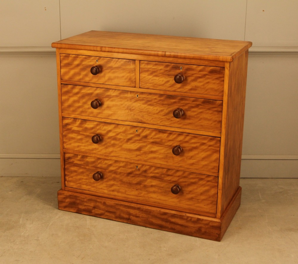 A Victorian stained birch chest of drawers featuring a two short over three long drawer configuration with turned wooden knobs and a solid plinth base. View VI
