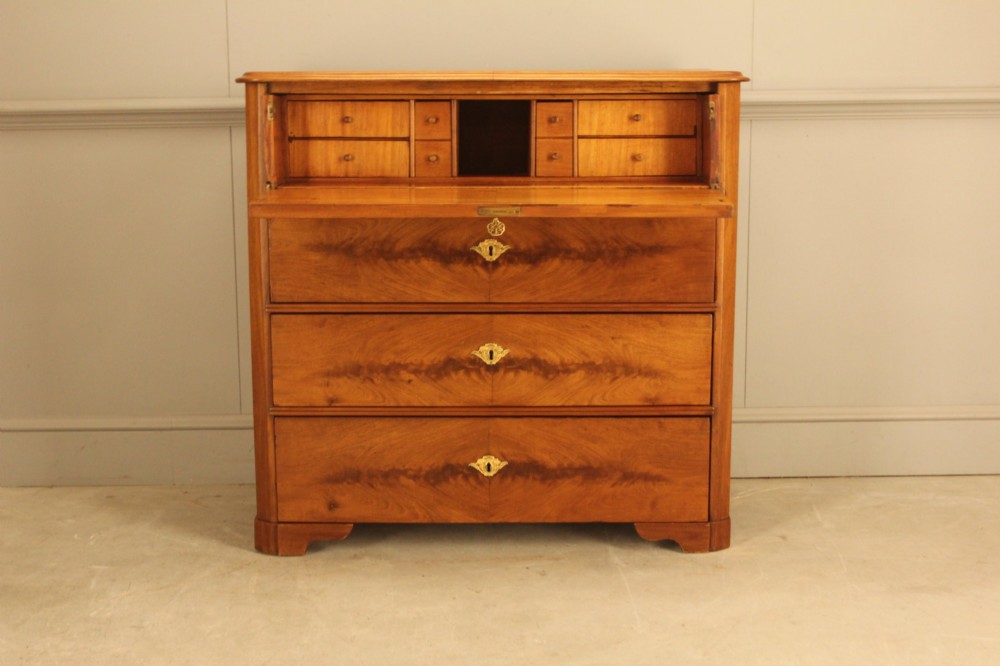 A nineteenth-century Swedish curl mahogany secretaire chest featuring three long drawers below a fold-down desk surface revealing fitted interior drawers.