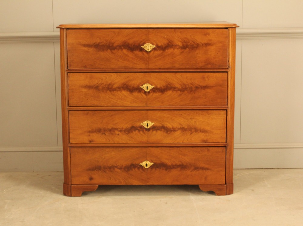 A nineteenth-century Swedish curl mahogany secretaire chest featuring three long drawers below a fold-down desk surface revealing fitted interior drawers. View II