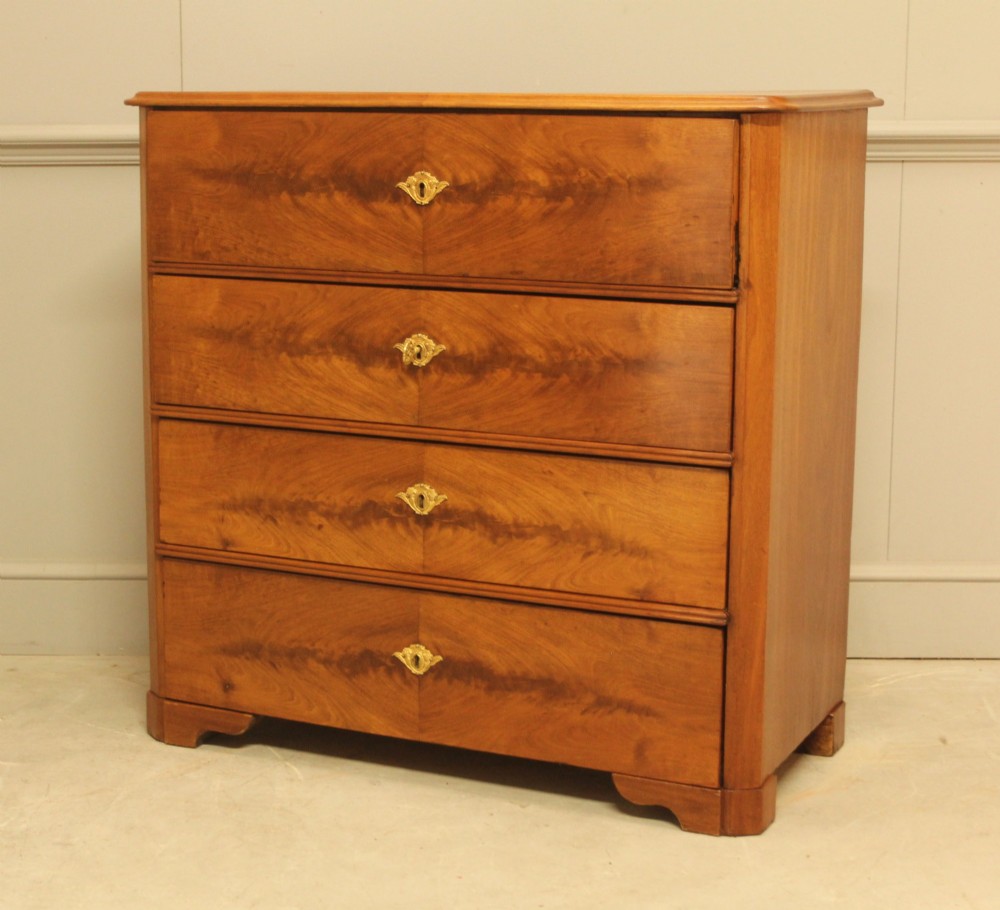 A nineteenth-century Swedish curl mahogany secretaire chest featuring three long drawers below a fold-down desk surface revealing fitted interior drawers. View IV