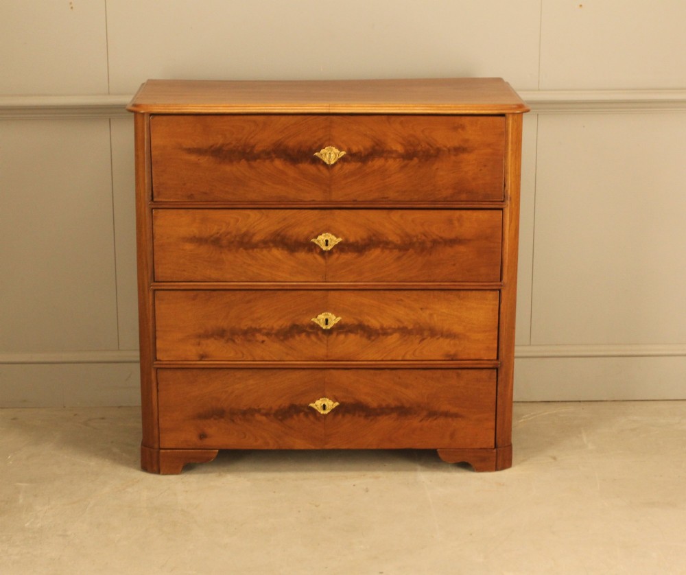 A nineteenth-century Swedish curl mahogany secretaire chest featuring three long drawers below a fold-down desk surface revealing fitted interior drawers. View V
