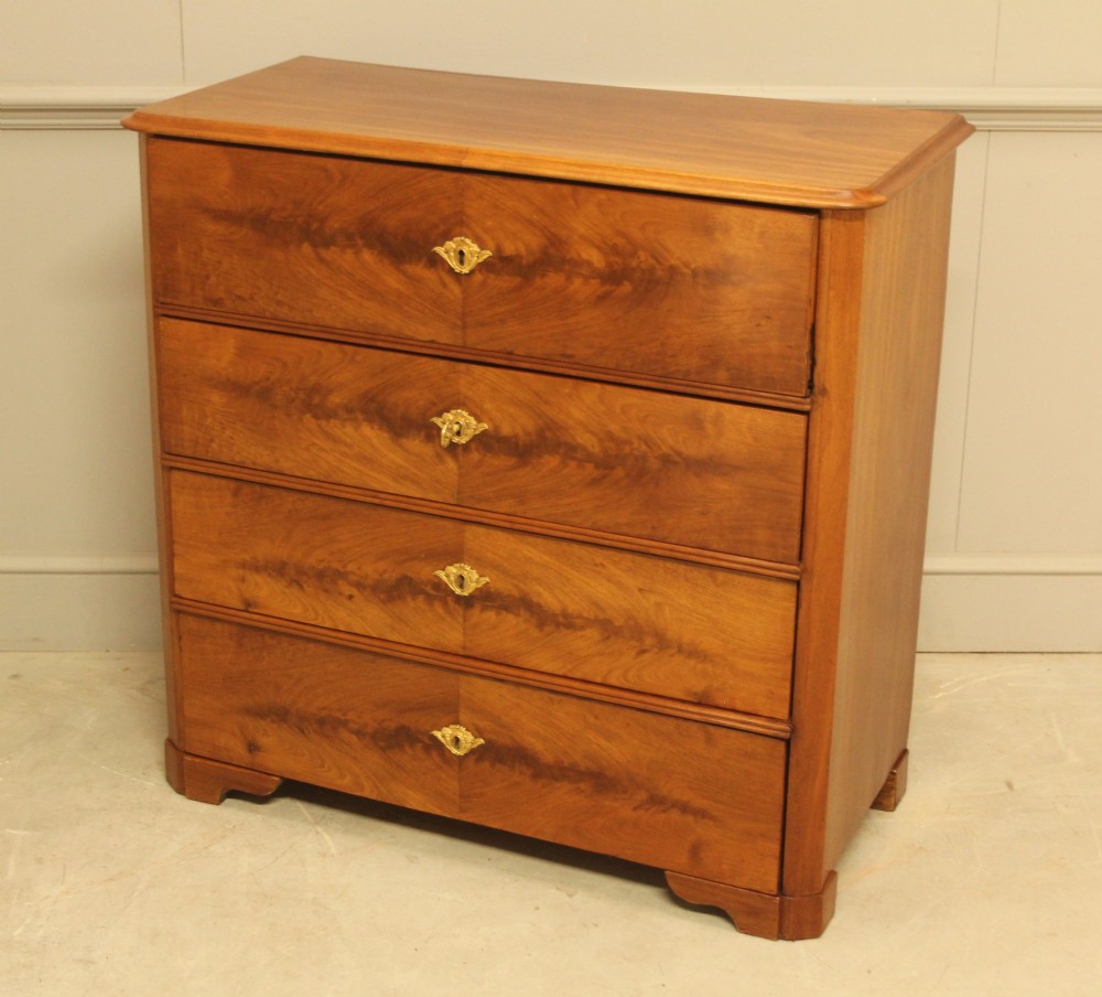 A nineteenth-century Swedish curl mahogany secretaire chest featuring three long drawers below a fold-down desk surface revealing fitted interior drawers. View VI