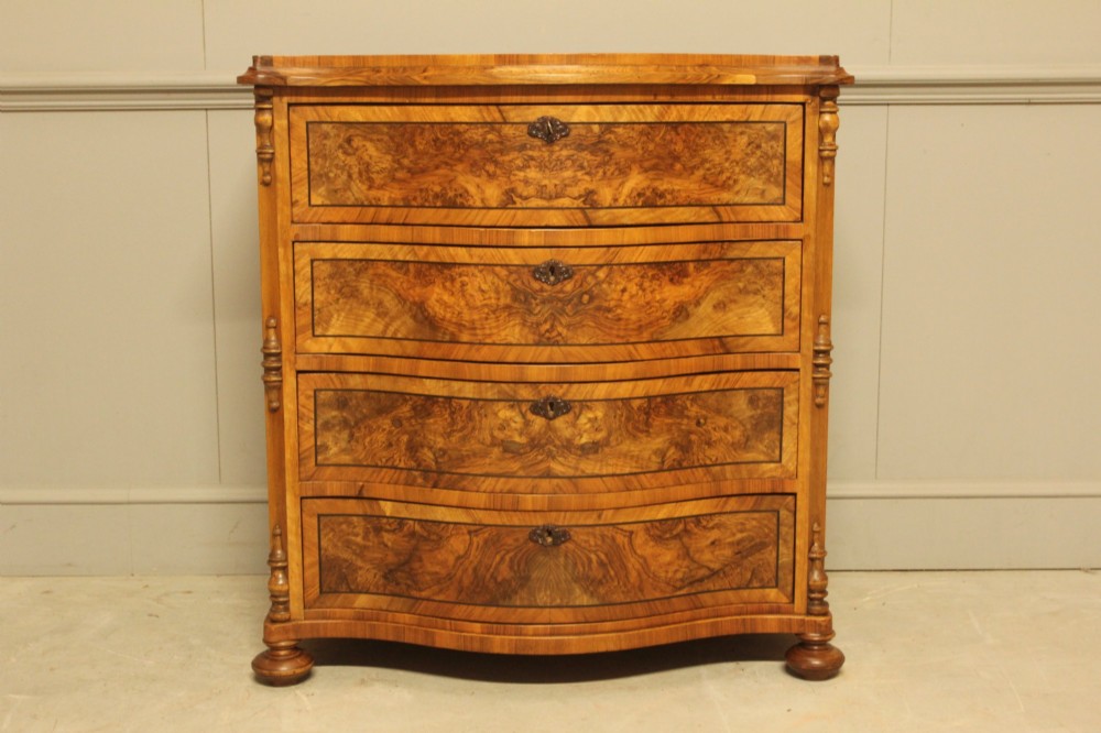 A 19th-century Swedish burr walnut chest featuring four serpentine-front drawers, bookmatched veneers, turned side pilasters, and bun feet.