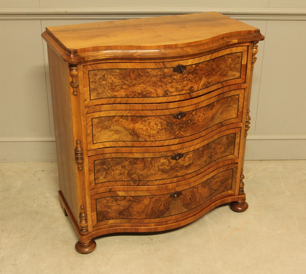 A 19th-century Swedish burr walnut chest featuring four serpentine-front drawers, bookmatched veneers, turned side pilasters, and bun feet. View V