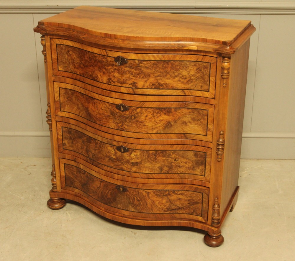 A 19th-century Swedish burr walnut chest featuring four serpentine-front drawers, bookmatched veneers, turned side pilasters, and bun feet. View VI