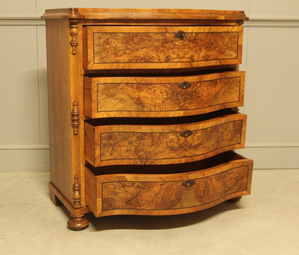 A 19th-century Swedish burr walnut chest featuring four serpentine-front drawers, bookmatched veneers, turned side pilasters, and bun feet. View VIII
