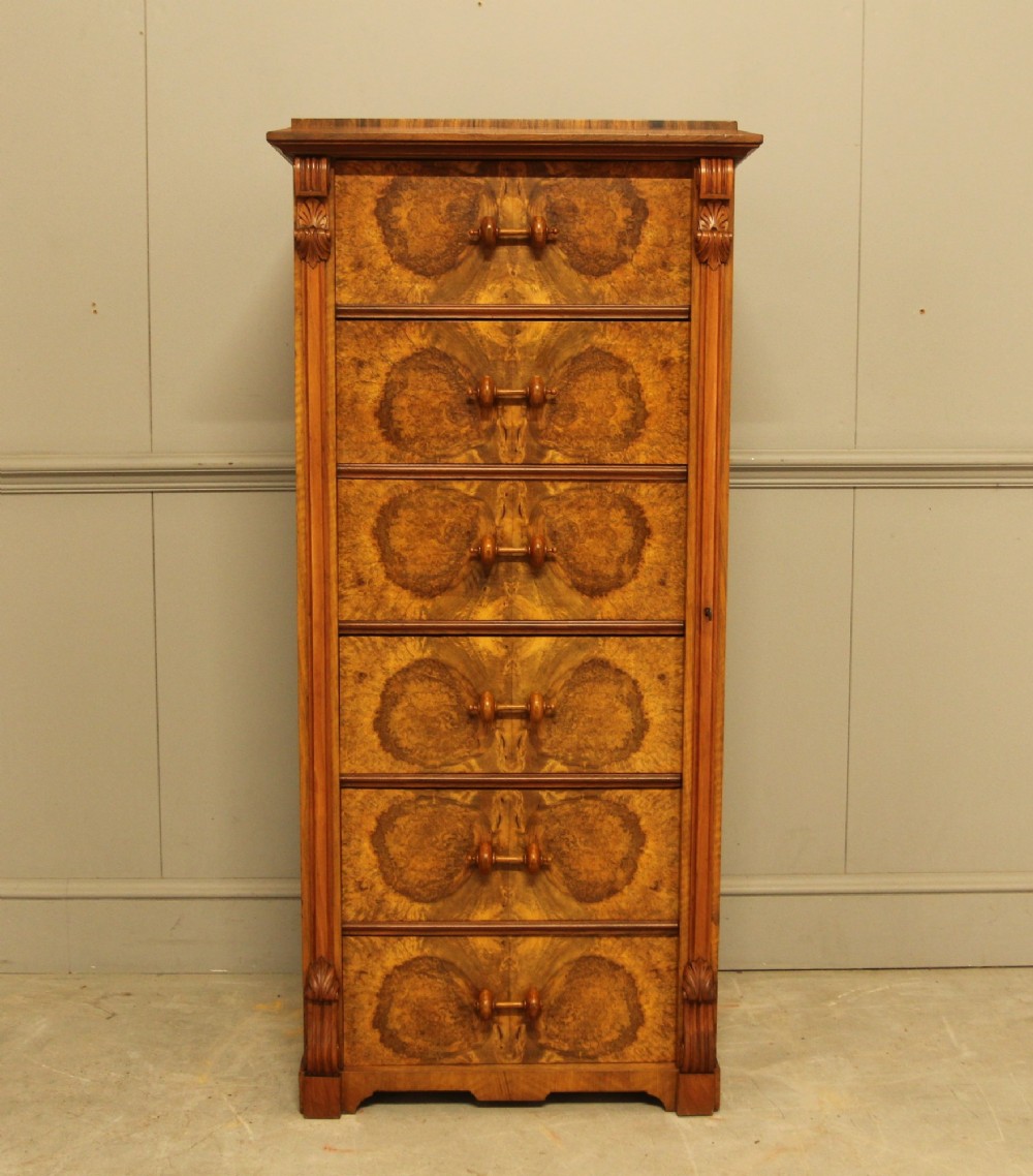 A tall 19th-century Swedish Wellington chest featuring six book-matched burr walnut drawers with turned handles, flanked by carved pilasters.