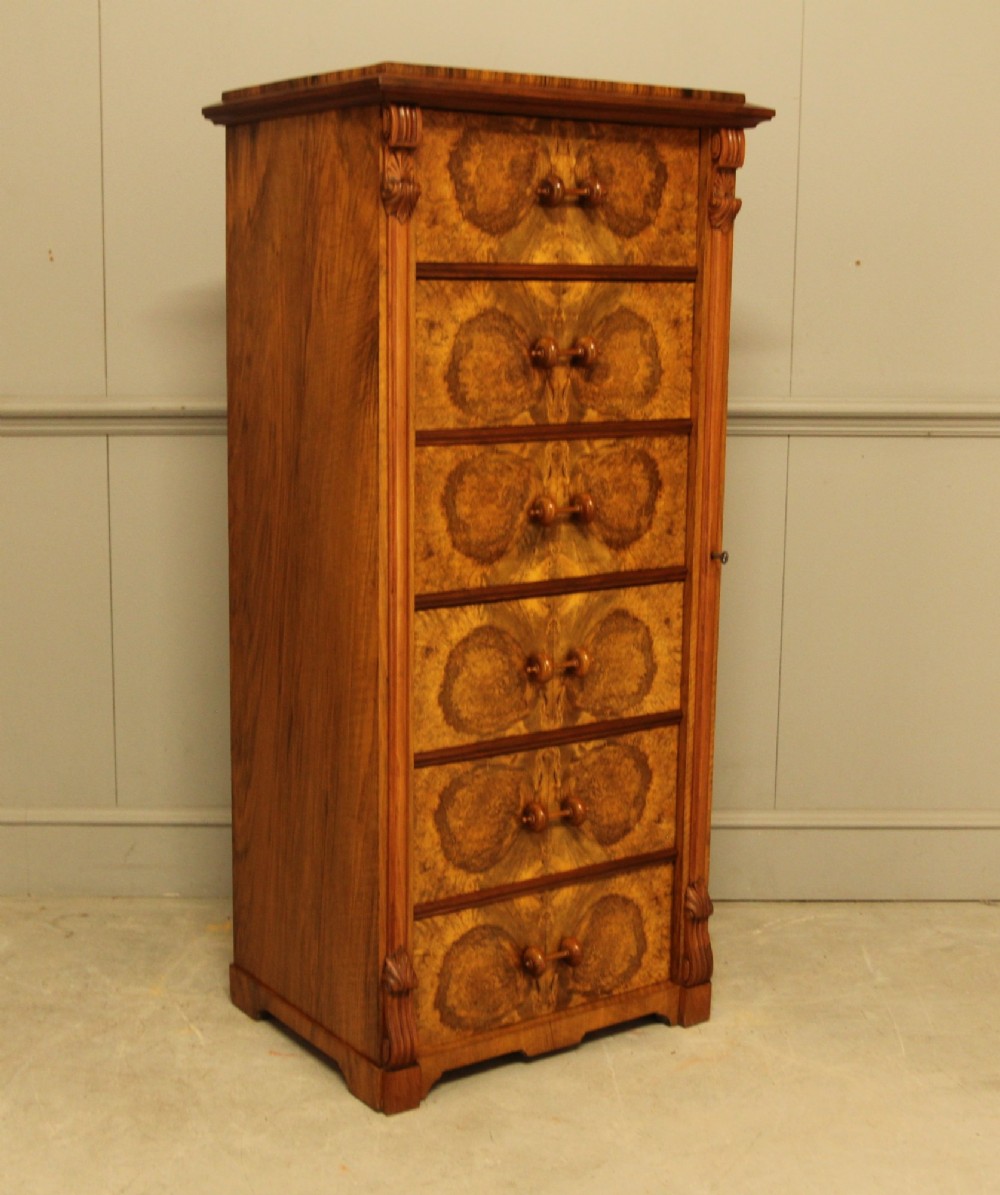 A tall 19th-century Swedish Wellington chest featuring six book-matched burr walnut drawers with turned handles, flanked by carved pilasters. View II