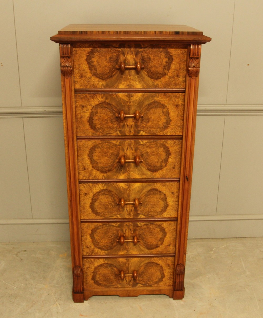 A tall 19th-century Swedish Wellington chest featuring six book-matched burr walnut drawers with turned handles, flanked by carved pilasters. View IV