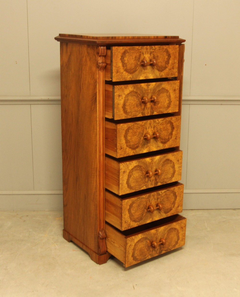A tall 19th-century Swedish Wellington chest featuring six book-matched burr walnut drawers with turned handles, flanked by carved pilasters. View VII