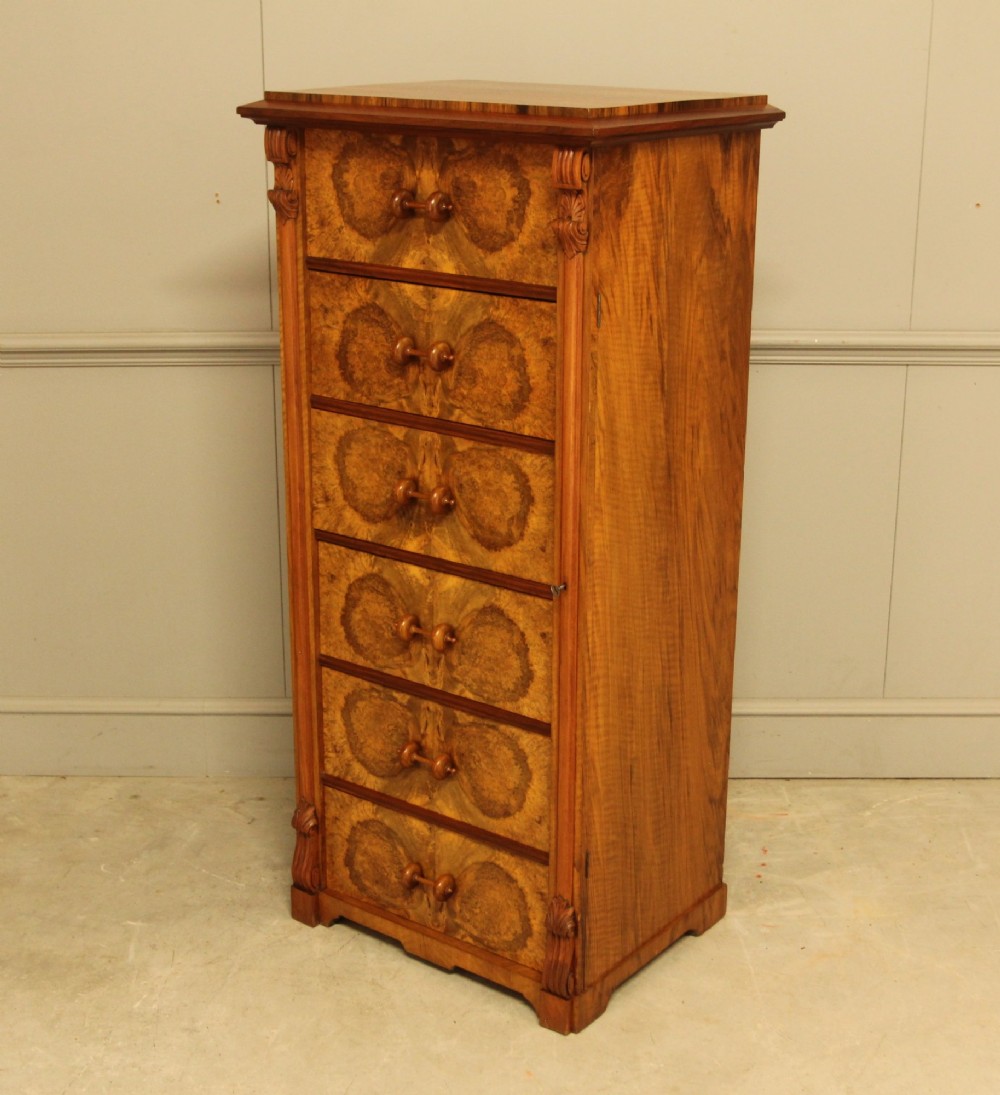 A tall 19th-century Swedish Wellington chest featuring six book-matched burr walnut drawers with turned handles, flanked by carved pilasters. View IX