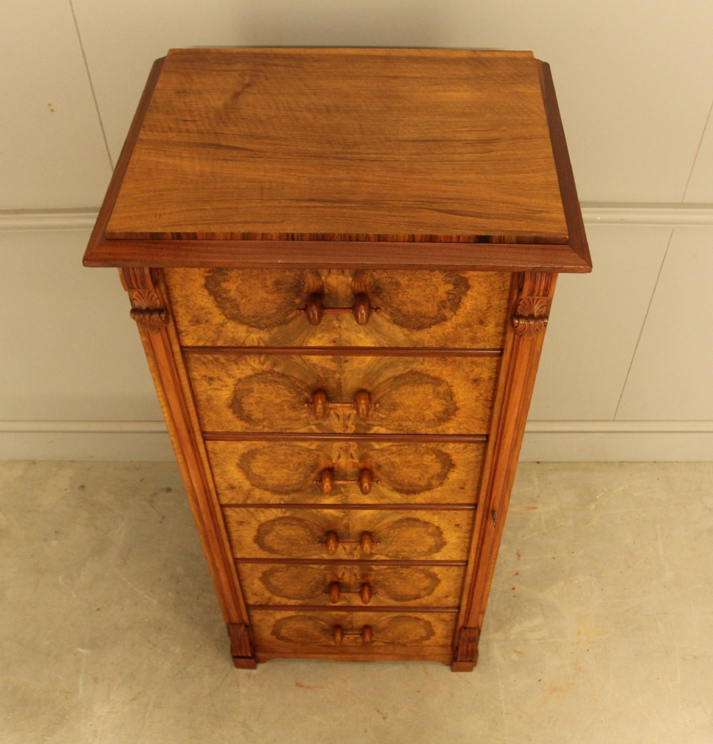 A tall 19th-century Swedish Wellington chest featuring six book-matched burr walnut drawers with turned handles, flanked by carved pilasters. View X
