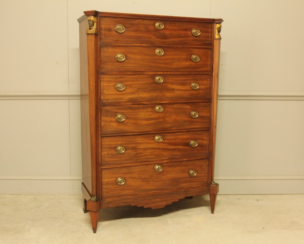 A French 19th-century mahogany tallboy chest of drawers featuring six drawers, brass ring handles, escutcheons, and fluted side pilasters topped with brass busts. View IV