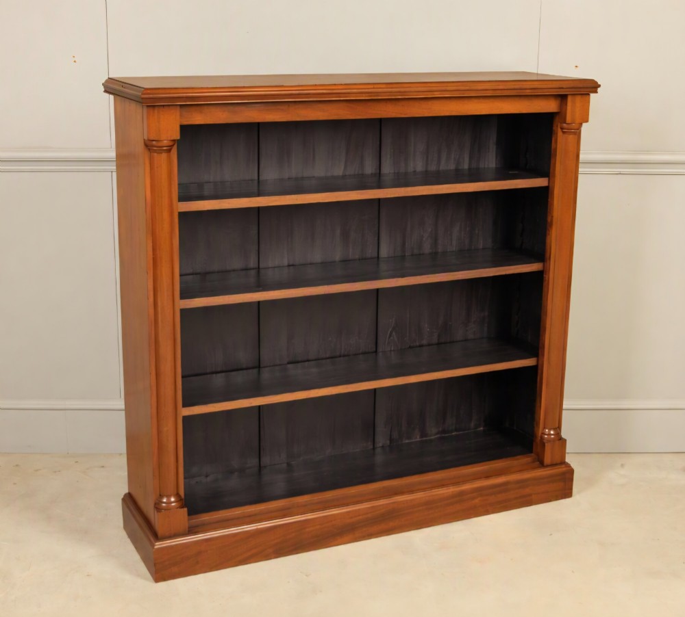 A Victorian open mahogany bookcase featuring four shelves flanked by turned pilasters on a solid plinth base.