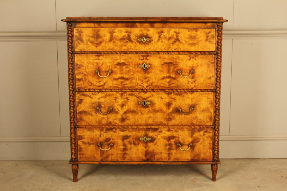 A nineteenth-century Swedish chest of drawers crafted from highly figured flame birch veneer, featuring four full-width drawers with brass drop handles, brass escutcheons, and spiral-twisted side columns.