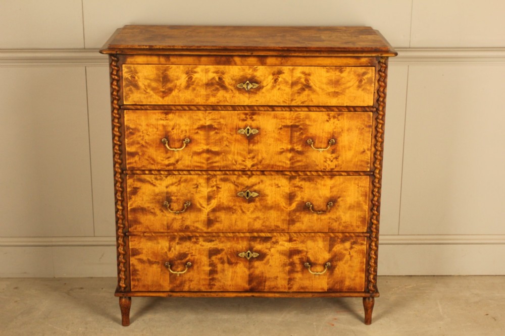 A nineteenth-century Swedish chest of drawers crafted from highly figured flame birch veneer, featuring four full-width drawers with brass drop handles, brass escutcheons, and spiral-twisted side columns. View IV