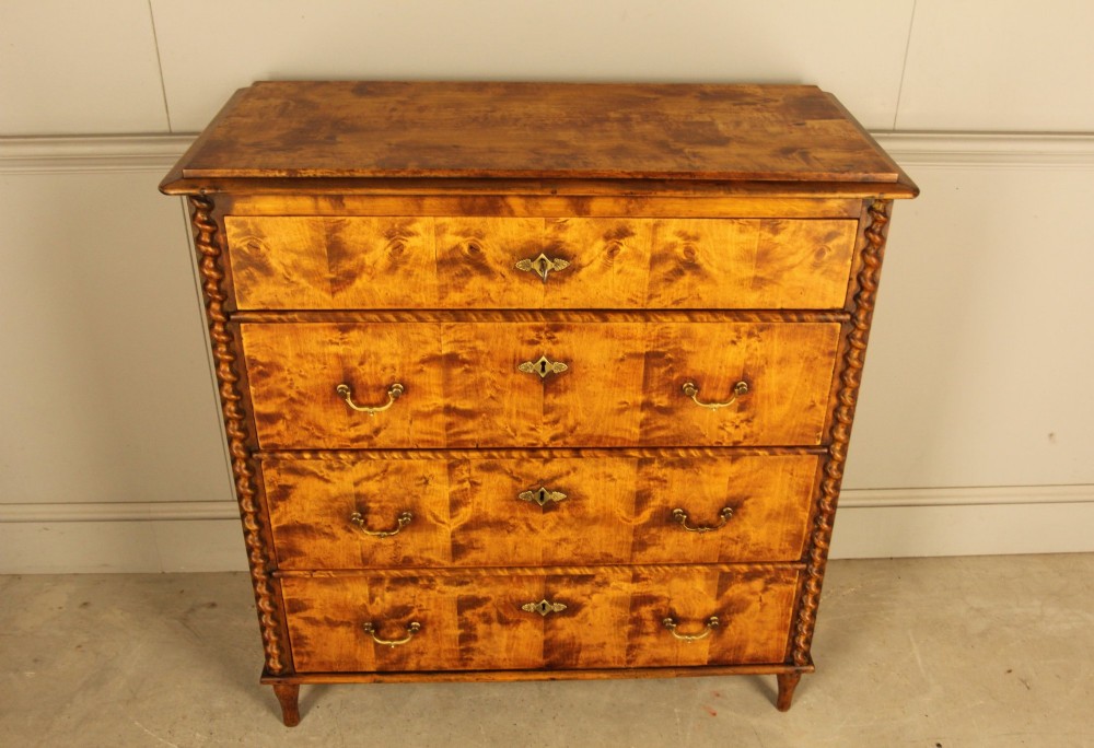 A nineteenth-century Swedish chest of drawers crafted from highly figured flame birch veneer, featuring four full-width drawers with brass drop handles, brass escutcheons, and spiral-twisted side columns. View VI