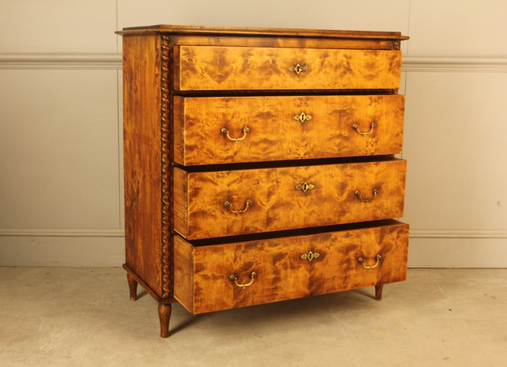 A nineteenth-century Swedish chest of drawers crafted from highly figured flame birch veneer, featuring four full-width drawers with brass drop handles, brass escutcheons, and spiral-twisted side columns. View VII