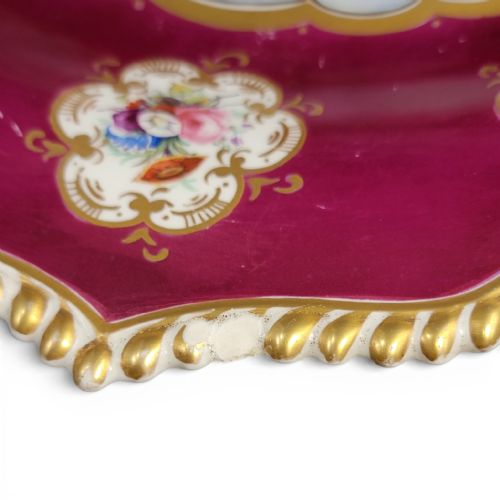 fig 3. An oval early 19th-century claret porcelain serving dish featuring gold scroll handles, floral border panels, and a central hand-painted scene of figures in a boat.
