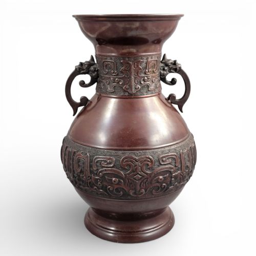 fig 3. A cast dark bronze Japanese archaistic hu vase featuring dragon head handles and intricate carved relief bands around the neck and waist.