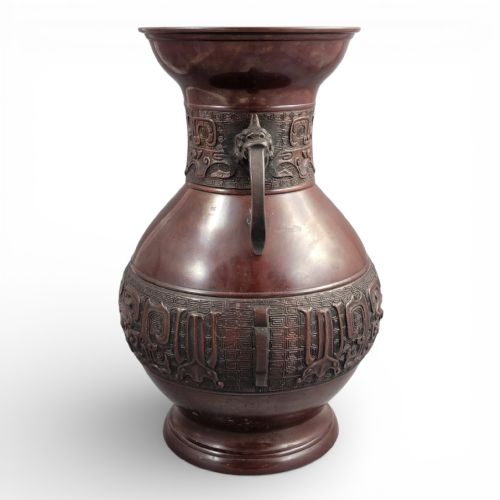 fig 4. A cast dark bronze Japanese archaistic hu vase featuring dragon head handles and intricate carved relief bands around the neck and waist.