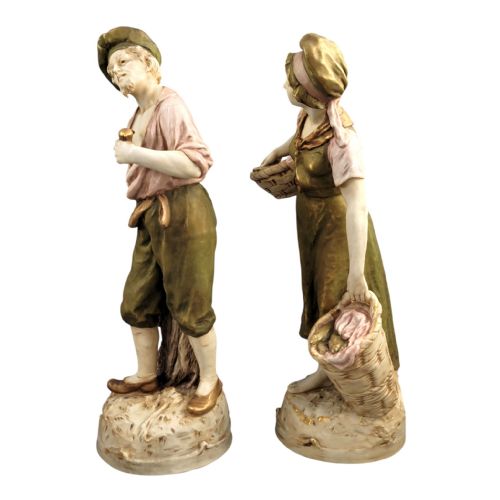 fig 2. A pair of antique Royal Dux porcelain figures depicting a fisherman with a pipe and a fisherwoman carrying baskets of fish, finished in muted green, pink, and gilt glazes.