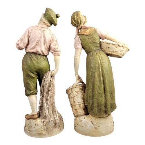 fig 3. A pair of antique Royal Dux porcelain figures depicting a fisherman with a pipe and a fisherwoman carrying baskets of fish, finished in muted green, pink, and gilt glazes.