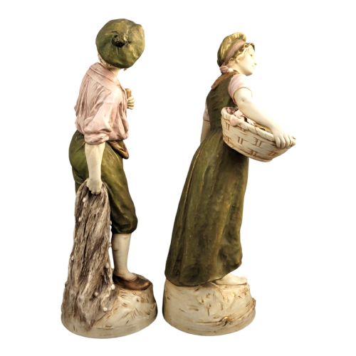 fig 4. A pair of antique Royal Dux porcelain figures depicting a fisherman with a pipe and a fisherwoman carrying baskets of fish, finished in muted green, pink, and gilt glazes.