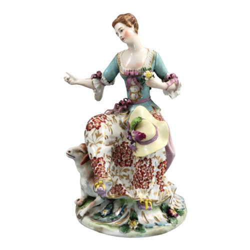 fig 1. A Samson Paris hand-painted porcelain figurine depicting a seated shepherdess with a floral skirt beside a resting lamb on a floral encrusted base.