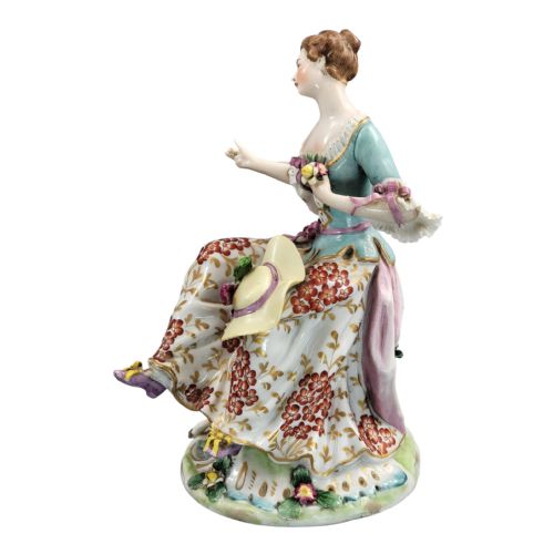 fig 2. A Samson Paris hand-painted porcelain figurine depicting a seated shepherdess with a floral skirt beside a resting lamb on a floral encrusted base.