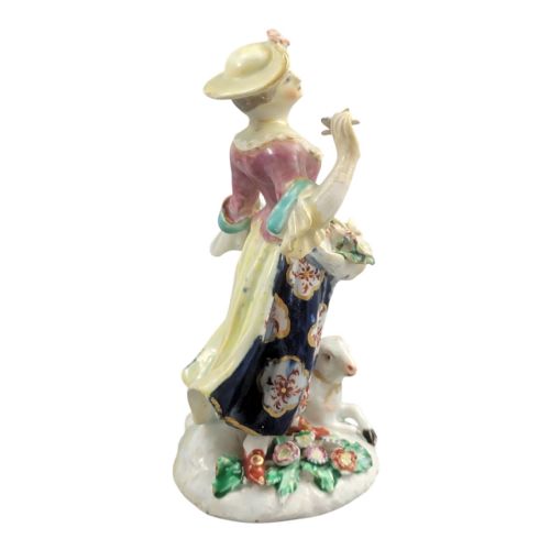 fig 3. An 18th-century Bow porcelain figurine depicting a lady in a patterned skirt and wide-brimmed hat holding flowers alongside a seated lamb.
