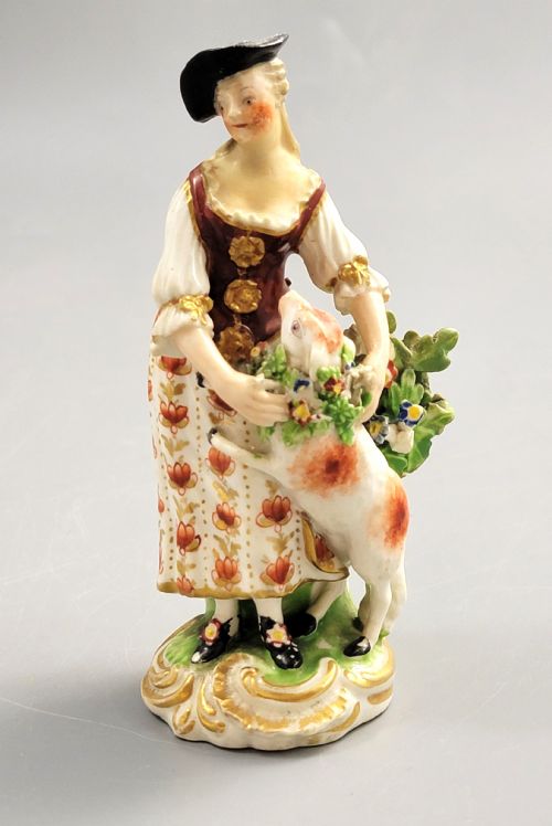 fig 1. An 18th-century Derby soft-paste porcelain figurine depicting a shepherdess with a lamb on a gilded Rococo scroll base.