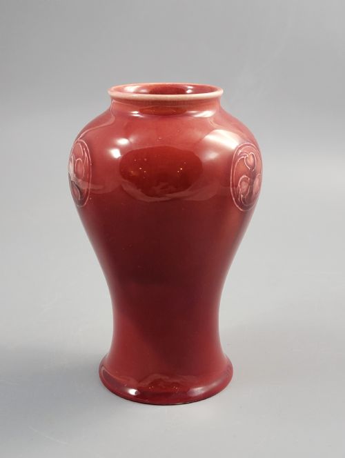 fig 2. A red glazed earthenware vase featuring a baluster shape with an embossed roundel medallion near the rim.