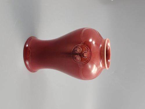 fig 3. A red glazed earthenware vase featuring a baluster shape with an embossed roundel medallion near the rim.