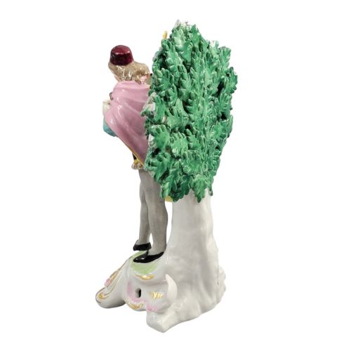 fig 2. A nineteenth-century French Samson porcelain figurine depicting a masked actor in a patterned jacket and cape standing before a flowering green tree backdrop.