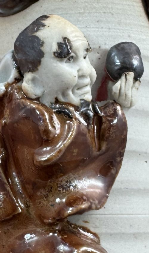 A Japanese Sumida Gawa stoneware vase featuring a ribbed cream body, dripping dark glaze along the flared rim, and an applied high-relief figure of a Rakan. View XII