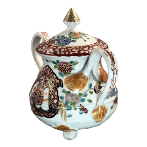 fig 1. A covered Japanese Imari porcelain sugar bowl featuring double side handles, a pointed gilded finial, and hand-painted samurai and floral motifs in red, blue, green, and gold enamels.