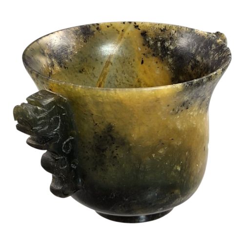 fig 2. A hand-carved mottled olive-green and dark ochre nephrite jade cup featuring carved handles on either side.