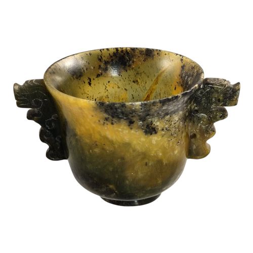fig 3. A hand-carved mottled olive-green and dark ochre nephrite jade cup featuring carved handles on either side.